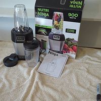Complete lot showing blender base, two cups with lids, instruction manual, and original product box.