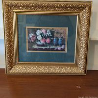 Full view of framed picture showing gold ornate frame and green matting with floral artwork inside