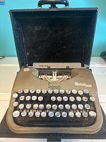 Front view of Simpson's Oliver Courier manual typewriter showing keyboard, brand logo, and case inside.