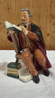 Front view of Royal Doulton figurine showing professor seated reading a book, detailed clothing and book stack visible