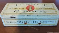 Top side of rectangular vintage tin labeled 'Turret Ogden's Liverpool Cigarettes' with red turret emblem.
