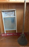 Photo showing all three items: wood and glass washboard, metal Red Rose Tea sign, and metal and wood washing plunger.