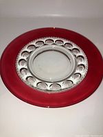 Single plate showing cranberry red rim with clear thumbprint pattern around center