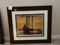 Frontal view of the framed painting showing sunset scene with silhouetted trees and bay, wooden frame and white/gold mat.