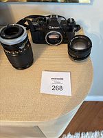 Canon AE-1 camera body with 70-210mm zoom lens and 50mm f/1.4 lens on table