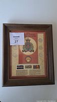 Full view of the framed coin and stamp collection commemorating the Royal Canadian Mounted Police in 1973, showing the wood frame and arrangement of coins and stamps.