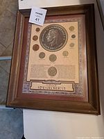 Framed vintage coin collection with central large coin and smaller coins around it along with text.