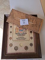 Wooden framed coin set with original box placed on top showing a map design.