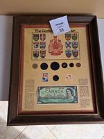 Full framed Canadian Centennial Collection showing mounted coins, stamps, and banknote with provincial shields and coat of arms.