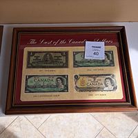 Framed collection showing all four Canadian one dollar bills from 1937 to 1975 issue dates.