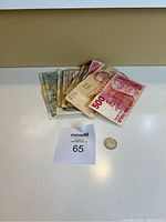 Top view of all banknotes fanned out with a coin placed beside them