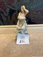 Full view of the Royal Doulton figurine showing the entire figure standing on a carpeted floor against a patterned background.