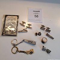 Overview of all items including keychains, cufflinks, tie bars, ring, earrings and commemorative stamp plate