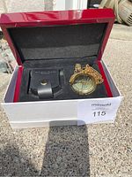 Pocket watch with chain and black leather pouch in a red polished wooden box with foam interior.