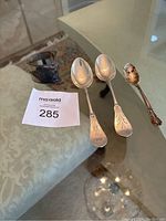 Photo showing two large sterling silver Birks spoons, one smaller tarnished silver spoon, and vintage silver napkin holder.