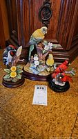 Complete set of three bird figurines displayed on floor with wooden cabinetry background