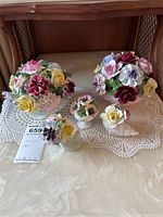Full set of five floral china figurines and crocheted doilies arranged on table.