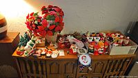 Wide view of table with various Christmas figurines, faux poinsettia plant, ceramic Christmas tree, and ornaments.