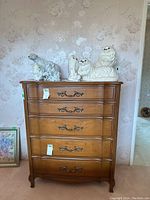 Front view of a tall wooden dresser with six drawers and brass handles. Some scuffs and scratches visible.