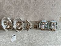 Full set of seven Victorian-style ceramic wall plaques displayed on carpet showing various figures and shapes
