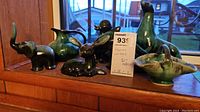 Photo showing six Blue Mountain style pottery animal figurines and one vase, all with green and black glaze.
