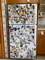 Full view of refrigerator covered with over 100 novelty magnets, mostly animal themed