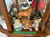 Front left corner of shelf with two brown dog figurines, bunny figurines and small duckling group
