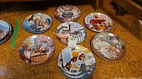 Seven Hamilton Collection collectible plates with cat themes shown laid out on the floor.