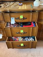 Three wooden dresser drawers opened showing various colorful scarves packed inside, including solid colors and printed patterns.