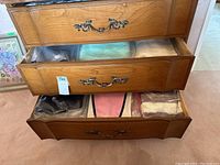 Three open wooden dresser drawers showing vintage ladies' knit sweaters individually wrapped in plastic bags.