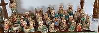 Wide view of entire collection showing multiple hand painted stoneware figurines from the English Woodlanders series, arranged on wooden surface.