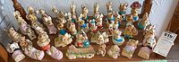 Full collection of Woodlanders stoneware animal figurines arranged on wooden chair, featuring rabbits in pastel clothing and mushrooms.