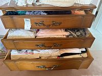 Photo of three drawers showing folded clothing including scarves, nighties, and t-shirts.