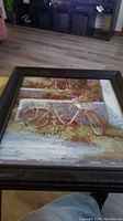 Photo showing full view of framed painting featuring a vintage bicycle leaning against a rustic wall with foliage around.