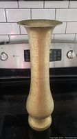 Front view of tall etched brass vase showing its full height and detailed patterns.