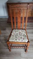 Front view of antique wood press back chair with floral patterned upholstered seat and turned legs