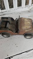 Side view of the vintage Tonka metal Jeep toy showing cabin, steering wheel, and rusted body.
