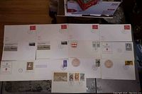 First photo showing a spread of multiple white envelopes with various stamps, postmarks and black/white printed images related to Canadian history and culture.