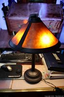 Front view of the lamp illuminated showing amber mica panels and bronze tone base.