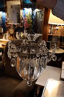 Full view of the crystal hall light showing the bronze frame, garnished with crystal flowers and hanging drops, suspended by a bronze chain with clear crystal top piece.