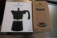 Original boxed Grosche Milano moka espresso maker and Grosche Bremen electric coffee grinder side by side on counter.