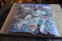 Photo showing a large plastic zip bag filled with loose used U.S. postage stamps of various colors and designs, mostly commemoratives.