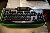 Full photo of the Logitech G15 gaming keyboard on its green box showing entire key layout and LCD screen.