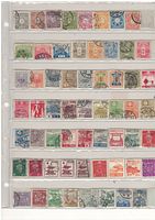 Full view of old Japanese postage stamps in rows on album page, mixed designs and values.
