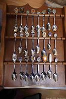 Full view of wooden spoon rack with 19 collectible souvenir spoons, showing variety of decorated handles and spoons in place