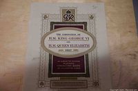 Photo of the front cover of the album titled 'The Coronation of H.M. King George VI and H.M. Queen Elizabeth 1937' by John Player & Son, featuring decorative elements and text indicating it is a souvenir album for cigarette cards.