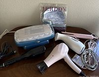 Photo showing the Jerdon mirror in packaging, two hair dryers in black and white, pink Lange hair straightener, and BaByliss Pro heated roller set in blue and white.