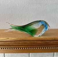 Side view of the Murano glass fish figurine showing the blue, green, and brown color blending and the smooth elongated form.