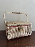 Front view of vintage wicker sewing basket with floral lid and handle, showing metal latch