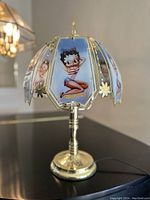 Full view of the vintage brass touch lamp showing the painted panels with Betty Boop in patriotic attire, with floral brass accents and round base.
